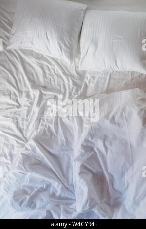 Messy lit avec oreillers et draps blancs close-up Banque D'Images