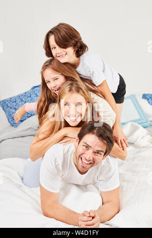 Famille heureuse avec deux enfants est heureusement lying together in bed dans la chambre à coucher Banque D'Images