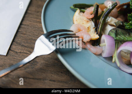 Un gros plan d'une fourche à l'empaler sur la crevette. Délicieuse Salade aux crevettes sur une table en bois. La crevette sur la fourchette. Banque D'Images