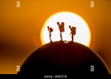 Sac à dos miniature figure personnes debout sur globe avec coucher et au lever du soleil le fond de ciel Banque D'Images