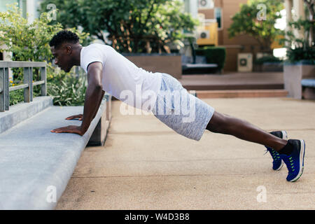 Young African American man doing push up dans city park. Sportive hommes personne exerçant à l'extérieur Banque D'Images