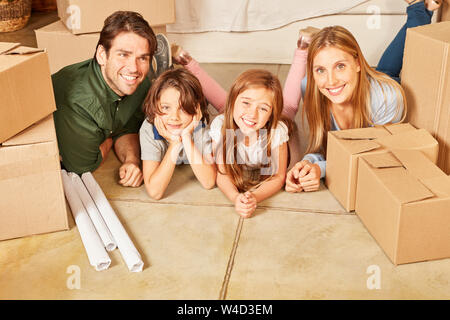 Famille heureuse avec deux enfants à la maison entre les boîtes de déménagement Banque D'Images