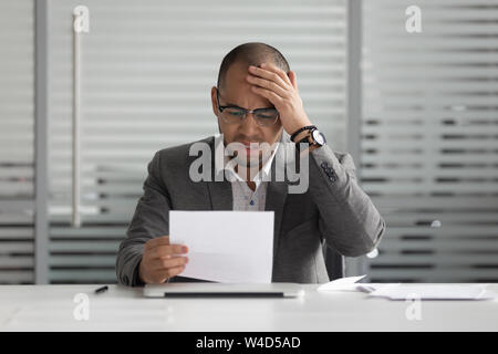 Frustrés mécontents african businessman reading mauvaise nouvelle en courrier A Banque D'Images