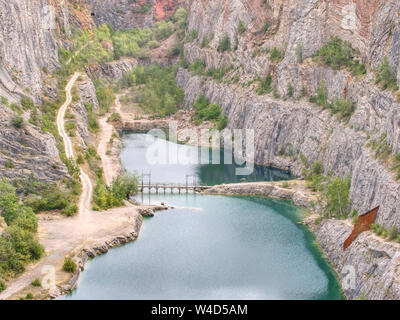 Grande ancienne carrière d'extraction de dolomie. Blue Lagoon en milieu avec pont en bois pour les touristes. Banque D'Images