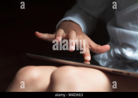 Libre vue avant du caucasien enfant part touchant l'écran d'un ordinateur tablette à la lumière du jour Banque D'Images