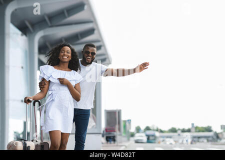 Young African couple standing près de l'aéroport d'essayer d'arrêter car Banque D'Images