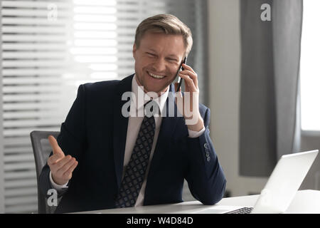 Happy businessman wearing suit rire talking on phone in office Banque D'Images