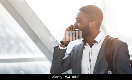 Toujours en contact. Afro Businessman Having Phone Talk in Airport Banque D'Images