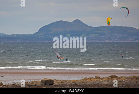 Longniddy virages, East Lothian, Scotland, UK. 22 juillet 2019. Conditions de vent exceptionnelle a encouragé plusieurs kitesurfers et windsurfers deux à relever le défi avec la magnifique toile de fond de siège d'Arthur, le château d'Édimbourg et le Forth Rail Bridge en arrière-plan. Banque D'Images