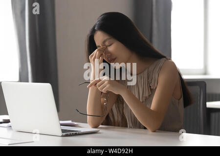 Surmené a souligné asian business woman holding glasses sentiment de fatigue oculaire Banque D'Images
