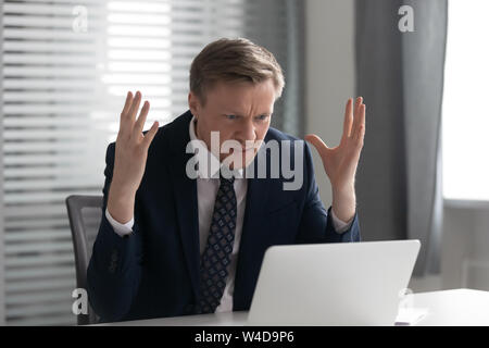 Agacé mad businessman wearing suit frustré avec problème d'ordinateur Banque D'Images