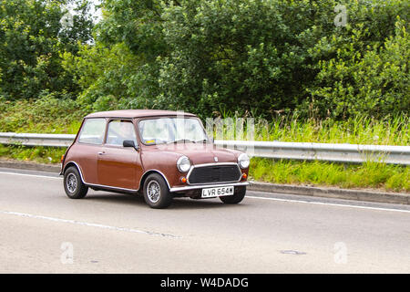 Années 1980 années 80 brun Morris vieux type Mini 850cc ; circulation automobile, véhicules en mouvement, voitures des années 80, conduite de véhicule sur les routes britanniques, moteurs, motorisation sur le réseau routier britannique autoroutier. Banque D'Images