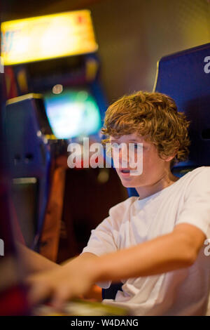 Teenage boy jouant un jeu vidéo à l'intérieur d'une arcade de jeux. Banque D'Images