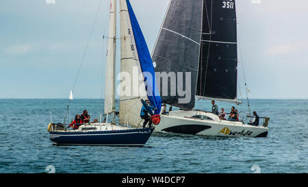 Travailler ensemble. Équipage de voiliers qui travaillent à la mise en place à la lumière spinnaker voile régate club vent pendant près de Greystones, mer d'Irlande. Banque D'Images
