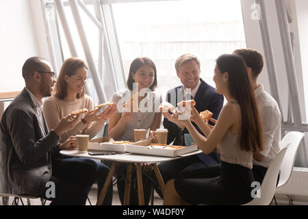 L'équipe multi ethnic friendly heureux s'amusant eating pizza together Banque D'Images