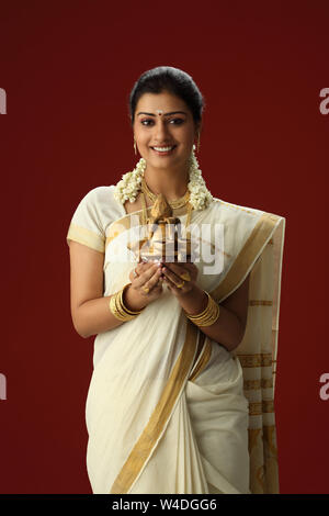 South Indian woman holding a kalash and smiling Banque D'Images