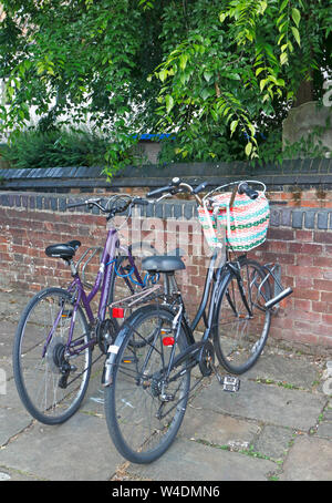 Deux dames vélos garés côte à côte près de la Maddermarket Theatre dans le centre-ville de Norwich, Norfolk, Angleterre, Royaume-Uni, Europe. Banque D'Images