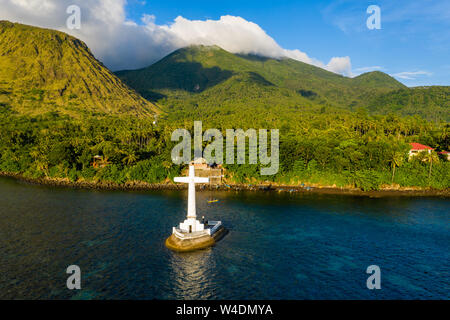 Vue aérienne de la lumière du soleil éclairant un soir d'or grand croix marquant un cimetière en contrebas de l'île de Camiguin tropicaux volcaniques Banque D'Images