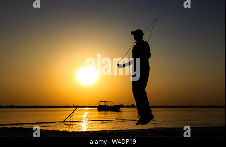 Jeune homme la corde à sauter à bord de mer. L'homme qui se profile le saut à la corde au coucher du soleil Banque D'Images