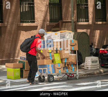 Un livreur de Lasership luttes dans la chaleur avec son chariot chargé d'achats de l'aime de Amazon, gommeux, et d'autres dans le quartier de Greenwich Village de New York le dimanche, Juillet 21, 2019 . (© Richard B. Levine) Banque D'Images