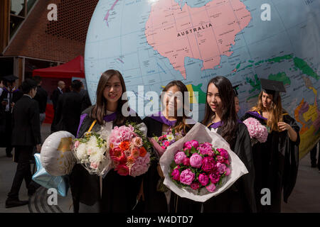 Sous la sculpture de l'artiste lauréat du Prix Turner Mark Wallinger intitulée "Le Monde à l'envers', les nouveaux diplômés directement après leur cérémonie de fin rencontrez la famille et les amis à l'extérieur de la London School of Economics (LSE), le 22 juillet 2019, à Londres, en Angleterre. "Le Monde à l'envers" est un grand globe politique, quatre mètres de diamètre, avec des États nations et frontières décrites mais avec la simple et révolutionnaire twist d'être inversée. La plupart des masses continentales se trouvent maintenant dans le "bas" avec les pays de l'hémisphère et les villes ré-étiquetés pour cette nouvelle orientation. Banque D'Images