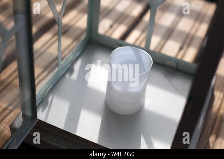 Lanternes blanc et brun sur un plancher en bois au cours d'une journée ensoleillée. Photographié en balcon avec verre rayé faisant belle clôture des ombres. Libre. Banque D'Images