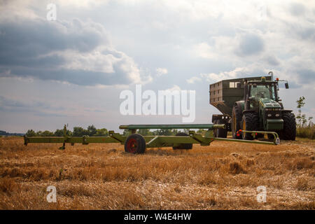 Kharkiv, Ukraine - le 16 juillet 2019 : Un tracteur pour la collecte du blé d'une moissonneuse-batteuse se dresse sur un champ de blé fauché contre un blue cloudy sky Banque D'Images