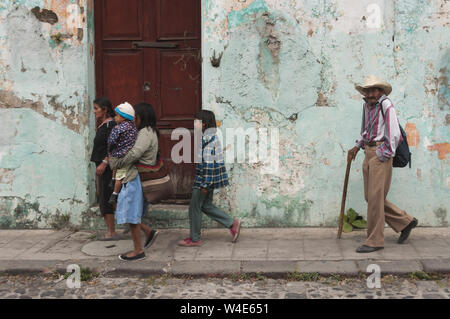 Au Guatemala, Antigua, scène de rue avec la famille marcher passé bâtiment coloré Banque D'Images