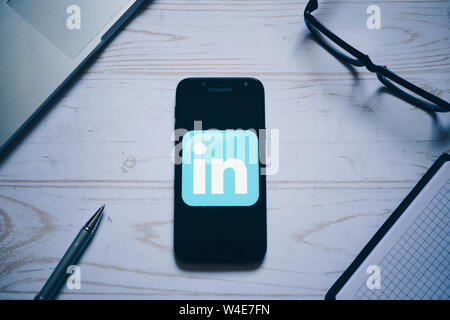 Nizhyn, Ukraine/ juillet-16-2019 : LinkedIn app logo sur l'écran de smartphone moderne. Mise à plat. Ordinateur portable, lunettes, carnet et un stylo sur l'arrière-plan. Social Banque D'Images