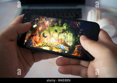 Nizhyn, Ukraine/Juillet-16-2019 : Hands holding smartphone et jouant de Hearthstone. Concept de jeu Android. Banque D'Images