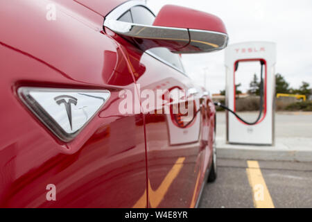 Tesla Model S rouge latérales comme le véhicule est suralimenté à Tesla CF Markham Supercharger. Banque D'Images