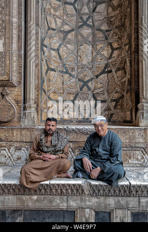 Les gardiens s'asseoir à l'entrée de l'Mosque-Madrassa massive du Sultan Hassan au Caire Islamique Banque D'Images