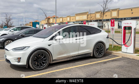 Tesla Model X blanc Modèle de charge avec S parallèlement à la Vaughan Mills Tesla Supercharger emplacement. Banque D'Images