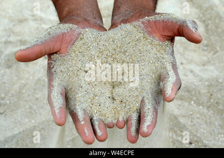 Les droits de l'ADN d'un homme et femme accroupie sur la plage de sable de Tybee avoir passer par leurs mains. Banque D'Images