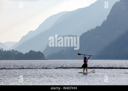 Jeune fille stand-up paddleboarding sur le lac Upper Campbell au Strathcona Park Lodge dans le parc provincial Strathcona, près de Campbell River, Vancouver Island Banque D'Images