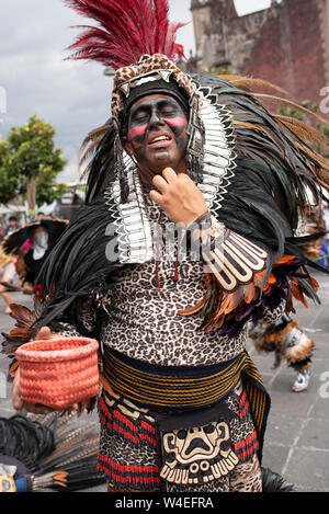 Danseur aztèque (après exécution de la rue) demander des contributions, tout en assouplissement de sa coiffure. Zocalo, Mexico, Mexique, CDMX. Jun 2019 Banque D'Images