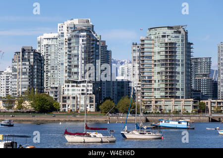 Bateaux dans le port de Vancouver, False Creek avec des condos et des montagnes enneigées en arrière-plan. Banque D'Images