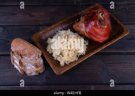 Jarret de porc avec de la choucroute sur une plaque de bois. Rustique l'Oktoberfest. Banque D'Images