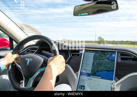 Man driving Red Tesla Model S avec la navigation sur 17' à côté de l'écran de Tesla. L'intérieur recouvert de cuir noir et gris. Banque D'Images