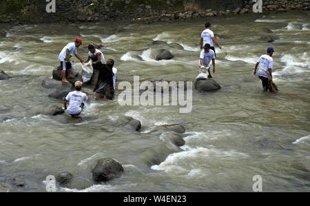 Bogor, Java ouest, Indonésie - Juillet 2019 : un groupe d'hommes travaillent ensemble dans la corbeille cueillette rivière Ciliwung. Banque D'Images