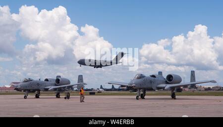 Deux des A-10 Thunderbolt II C'est attendre pour le décollage comme un C-17 Globemaster III vole au-dessus de lui à Patrick Air Force Base, en Floride, le 16 juillet 2019. Le A-10C Thunderbolt II pèse 29 000 livres, et a 9 065 livres de poussée par chacun des moteurs de l'appareil. (U.S. Air Force photo de Taylor NEF) Banque D'Images