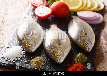 Matières premières matières premières fraîches poisson Sarpa salpa au citron, légumes et épices libre sur une liste de sélection sur une table. L'horizontale Banque D'Images