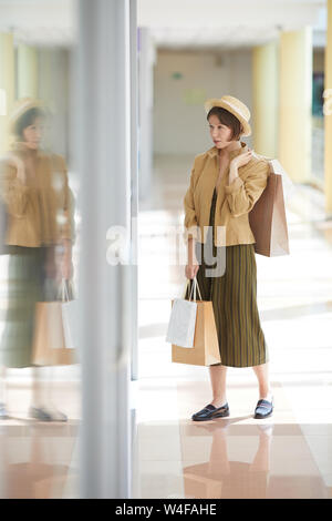 Belle dame élégante au chapeau de paille bien tenue et l'affichage de la boutique de vêtements d'un mannequin par Banque D'Images