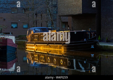 Le soleil qui attrape un bateau amarré quai de pommes de terre par les appartements, sur le Canal de Bridgewater à Castlefield, Manchester, Angleterre, RU Banque D'Images