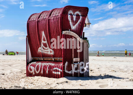 Chaise de plage avec l'inscription "Dieu  = amour'. Plage de l'Eglise oecuménique président de l'Evangelical et Eglise catholique se trouve dans la saison d'été 2019 sur la plage de l'île de la Frise orientale Spiekeroog, Allemagne --- Strandkorb mit der Aufschrift 'GOTT  = LIEBE". Ökumenischer Kirchen-Strandkorb und der Evangelischen Kirche steht in der katholischen Sommersaison 2019 am Strand der ostfriesischen Insel Spiekeroog, Deutschland Banque D'Images