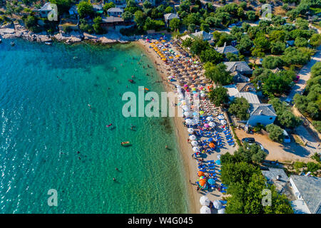 Vue aérienne de l'Aliki Beach avec parasols colorés, à l'île de Thassos, Grèce. Piscine personnes en mer Banque D'Images