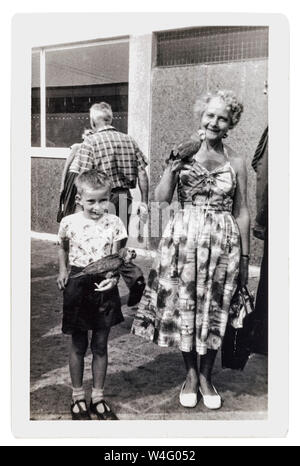 Petit garçon avec sa grand-mère holding perroquets à Clarence Pier fête foraine Banque D'Images