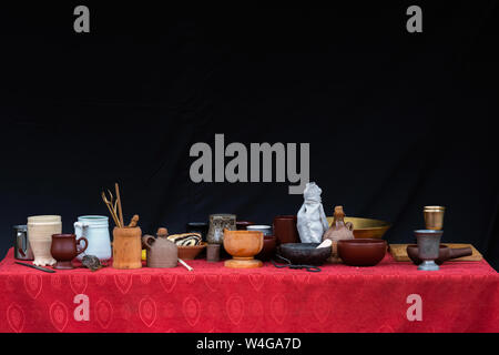 A beaucoup d'argile tasses, casseroles, assiettes, vases et autres plats sur le dessus de table avec nappe rouge et noir fond Banque D'Images