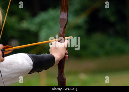 Archer détient son arc, visant à la cible. La compétition de tir à l'activité de plein air, Banque D'Images