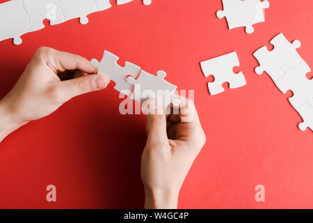 Portrait of man holding white pièces du puzzle en main sur red Banque D'Images